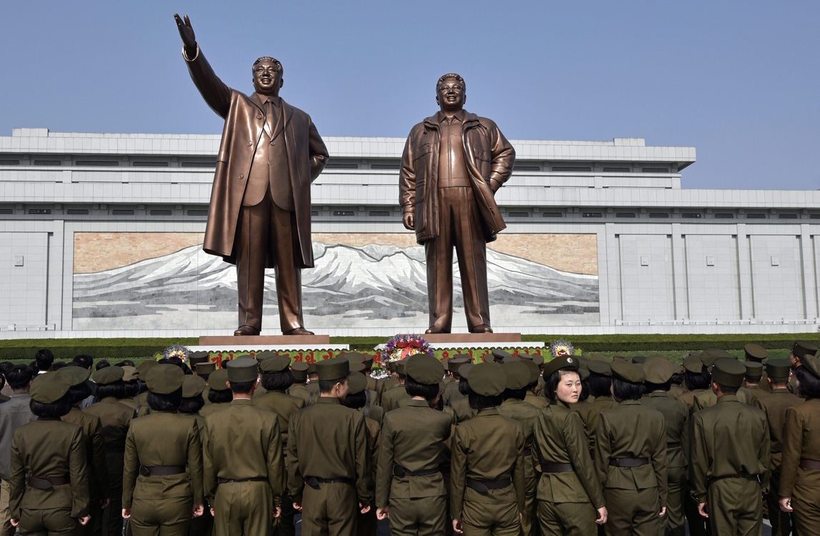 Észak-koreai katonák Kim Ir Szen és Kim Dzsong Il szobrai előtt Phenjanban