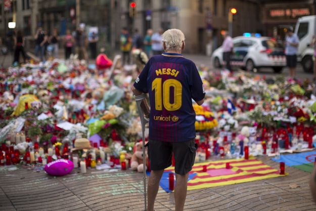 Egy férfi az áldozatok emlékére elhelyezett mécsesek és virágok előtt