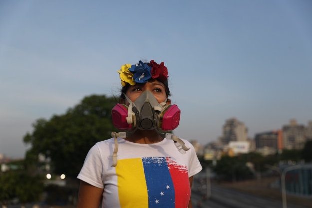 Juan Guaidó venezuelai parlamenti elnök, ellenzéki vezető egyik támogatója gázmaszkban a caracasi Carlota légi támaszpontnál tartott tüntetésen 2019. április 30