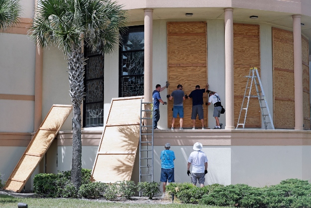 A munkások bedeszkázzák a Santa Maria del Mar katolikus templom ablakait a floridai Flagler Beach településen 2019. augusztus 30-án.