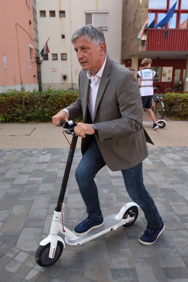 Az elektromos rollerrel érkező Grezsa István polgármesterjelölt sajtótájékoztatót tart a hódmezővásárhelyi Dr. Rapcsák András utcában 2019.