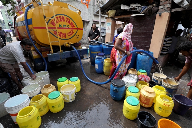 Tartálykocsiból folyó ivóvízzel töltik meg műanyag edényeiket az emberek az indiai Kolkatában 2019. július 9-én.