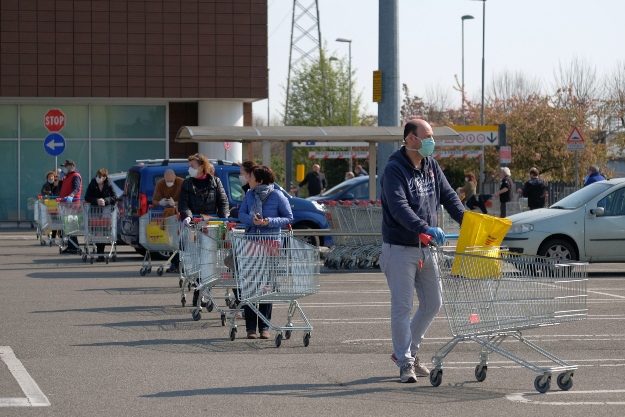 Vásárlók állnak hosszú sorban egy szupermarket előtt a koronavírus-járvány miatt bevezetett, a mozgást korlátozó tilalom idején Milánóban 2020. március 21-én.
