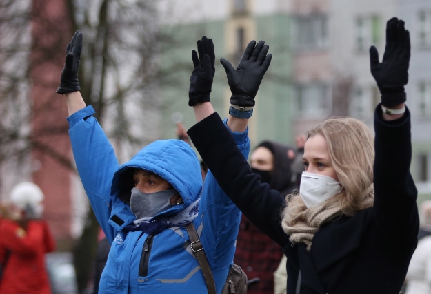 Magasba tartják karjukat a rohamrendőrökkel szemben állva az augusztus 9-i elnökválasztás eredménye ellen tüntetők Minszkben 2020. november 22-én.