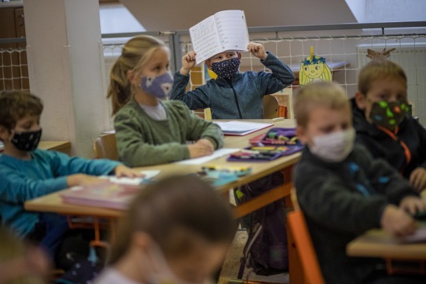 A koronavírus-járvány miatt védőmaszkot viselő tanuló a házi feladatát mutatja egy prágai iskolában 2020. november 18-án, amikor az általános iskolák első és má