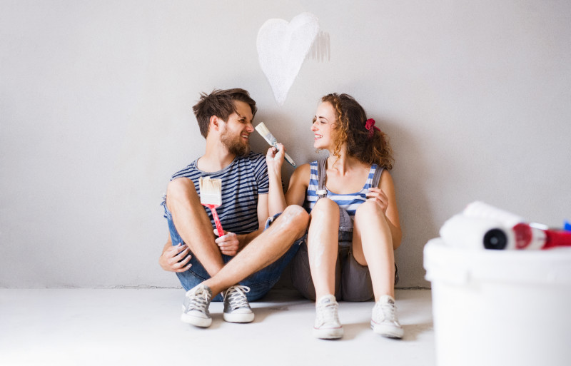 Young couple in love painting walls in their new home.