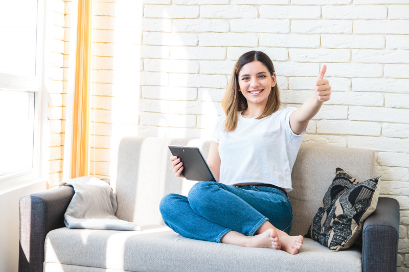 Technology, internet and people concept - happy attractive woman with tablet computer showing thumbs up at home