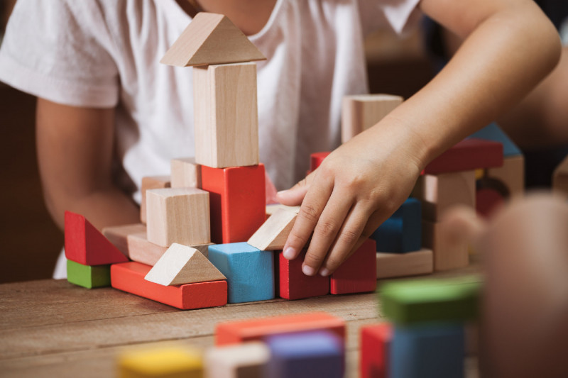 Focus on child's hand playing with colorful wooden blocks in vi